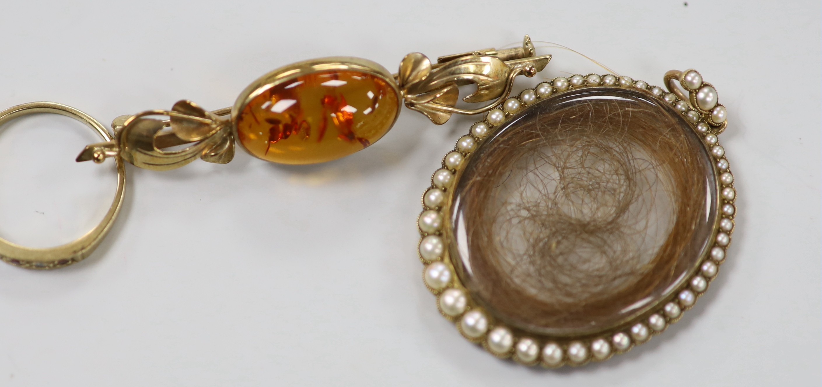 A 19th century yellow metal and split pearl mounted glazed mourning locket pendant containing a lock of hair, overall 48mm, a modern 9ct gold and gem set half hoop ring and a 9ct gold and amber set brooch.